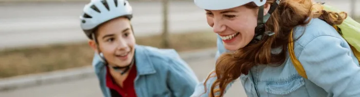Une femme et un garçon portant des casques roulent à trottinette.