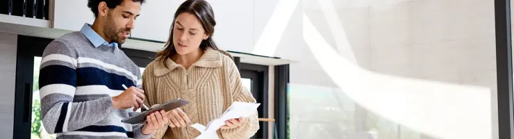 Un homme et une femme se tiennent dans une cuisine, examinant un document ensemble.