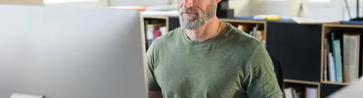 Un homme assis à un bureau devant un ordinateur, concentré sur son travail.