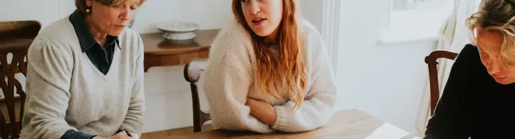 Trois personnes assises à une table, discutant et écrivant sur un papier