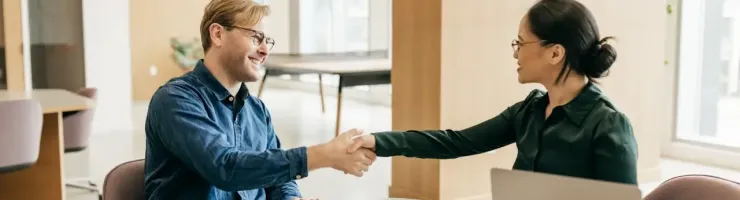 Deux professionnels échangent une poignée de main dans un bureau.