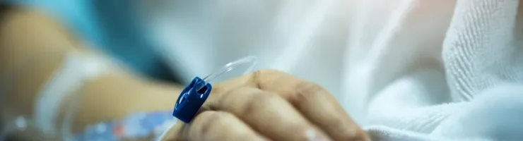 Détail de la main d'un patient à l'hôpital avec un cathéter pour perfusion intraveineuse.