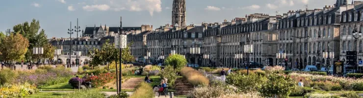 Bordeaux : grand parc avec pelouse et fleurs, longue flèche d'église à l'arrière-plan.
