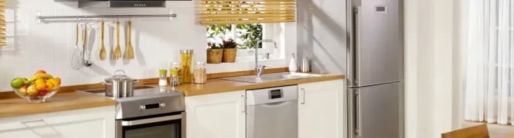 Cuisine lumineuse avec meubles blancs, plan de travail en bois, électroménager inox et table à manger.