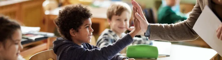 Élève souriant dans une salle de classe faisant un tope là avec son enseignant.