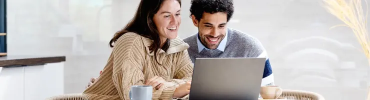 Un homme et une femme avec le sourire assis à une table, regardant ensemble quelque chose sur l'ordinateur portable.