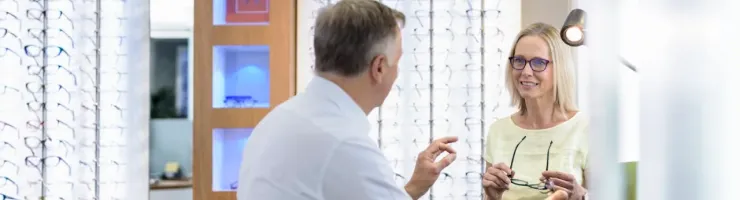 Opticien et cliente choisissant des lunettes dans un magasin d'optique.