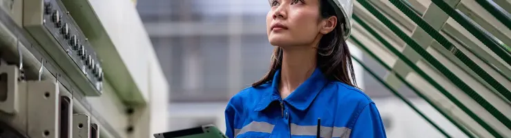 Technicienne en combinaison de travail inspectant une installation électrique.