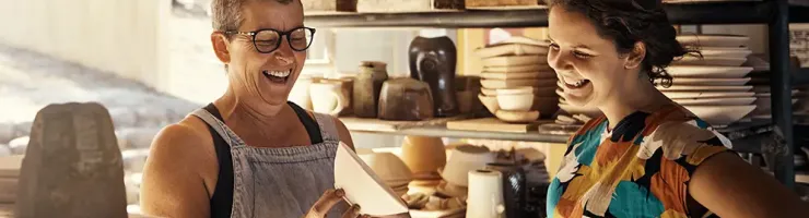 Artisane potière échangeant avec une cliente dans son atelier de céramique
