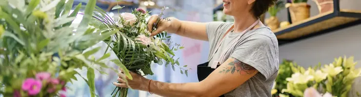 Fleuriste composant un bouquet de fleurs dans sa boutique.