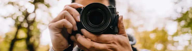Photographe professionnel prenant une photo en extérieur avec un appareil reflex.