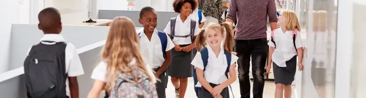 Un groupe d'enfants marche dans un couloir, accompagné d'un homme et d'une femme au centre.