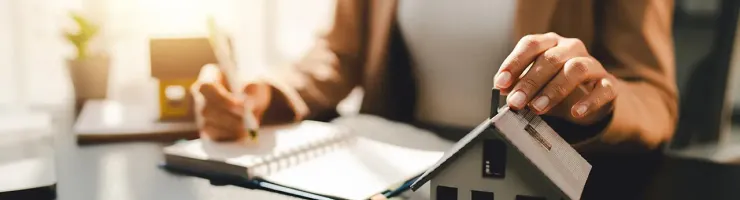 Une femme signe un contrat avec un agent immobilier dans un bureau, entourée de documents