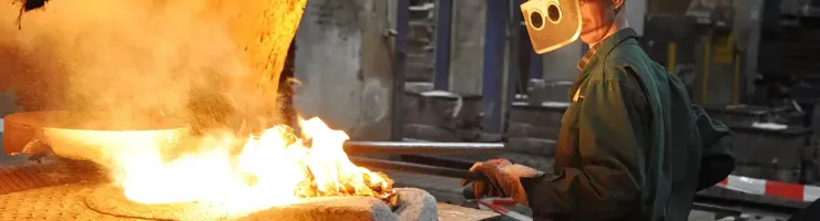 Un homme portant un casque de sécurité travaille sur un objet en métal dans un environnement industriel.