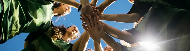 Une équipe féminine en maillots verts se tenant par la main, formant un cercle.