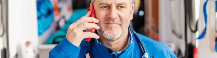 Un homme en chemise bleue parle au téléphone portable, affichant une expression concentrée.