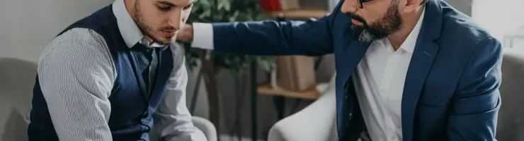 Un thérapeute soutient son patient en posant sa main sur son épaule.
