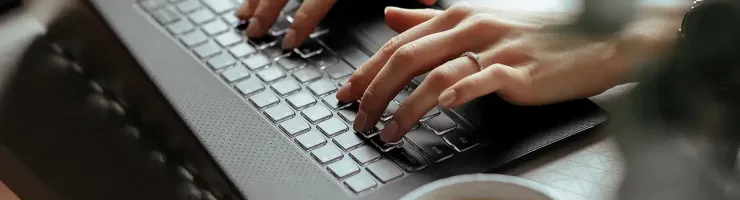 Mains en train de saisir sur le clavier d'un ordinateur portable.