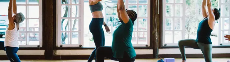 Un groupe de personnes pratiquant le yoga dans une salle de sport, concentrées et en pleine séance d'exercice.