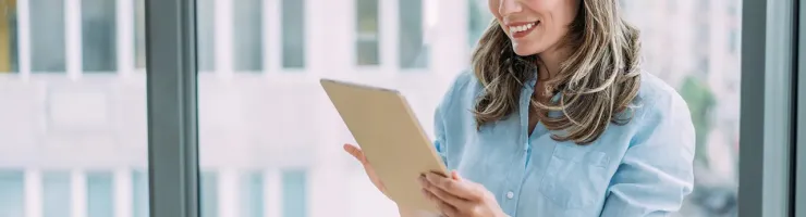 Femme consultant une tablette numérique dans un bureau urbain.