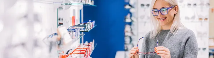 Femme essayant des lunettes de vue dans une boutique d’optique.