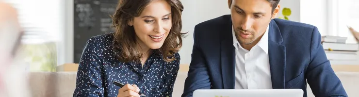 Deux personnes analysant des documents sur un ordinateur portable.
