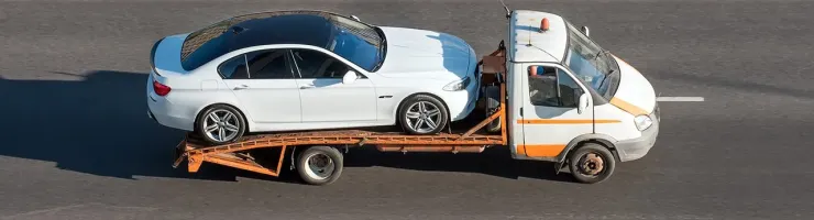 Un camion de dépannage tire une voiture blanche sur une route dégagée