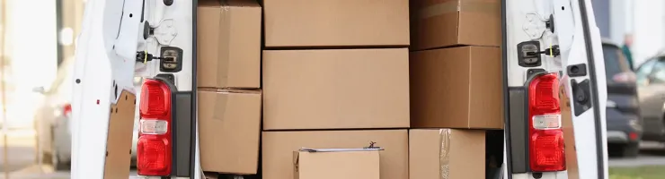 Une camionnette blanche chargée de cartons à l'arrière, prête pour le transport.