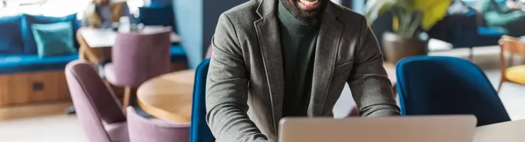 Un homme assis à une table, utilisant un ordinateur portable, concentré sur son travail.