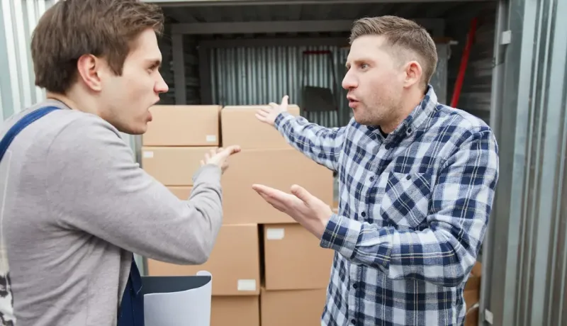 Deux hommes en train d'échanger vigoureusement concernant les cartons à l'intérieur d'un local.
