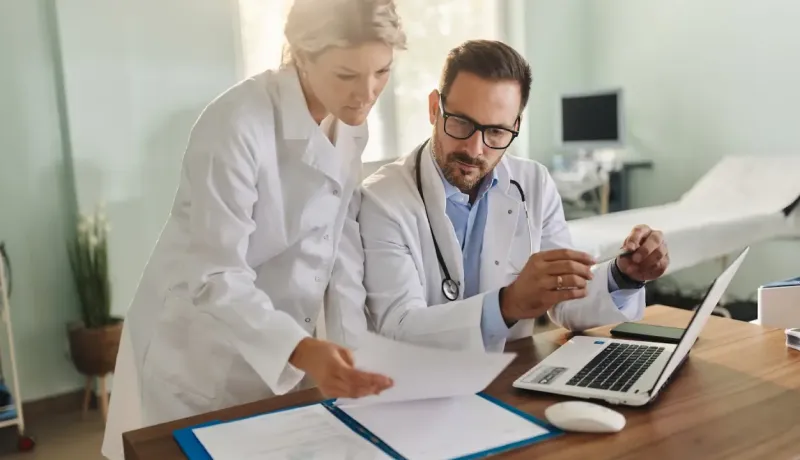 Une femme et homme médecin en train de regarder un document médical.