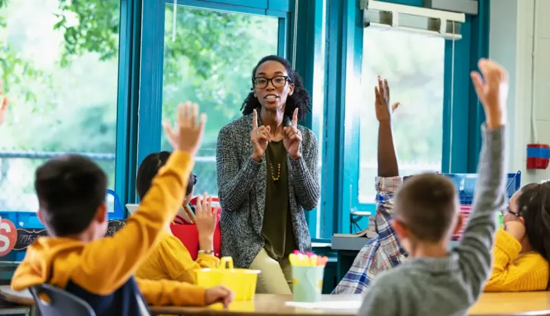 Des élèves lèvent la main en classe.
