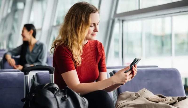 Une femme consulte son téléphone portable à l'aéroport.