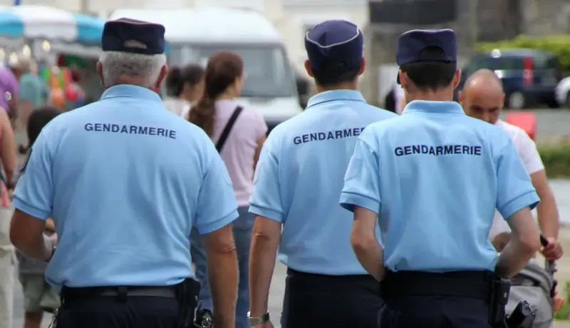 Trois gendarmes vus de dos en patrouille ou en inspection.