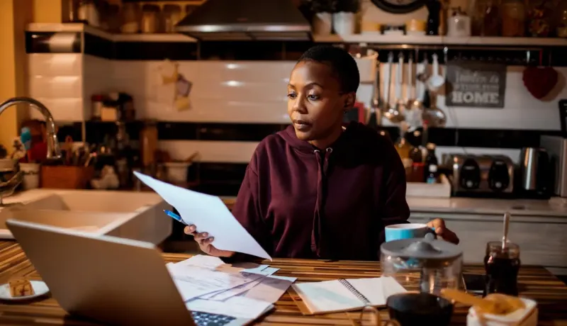 Une femme travaille sur un ordinateur portable dans une cuisine.