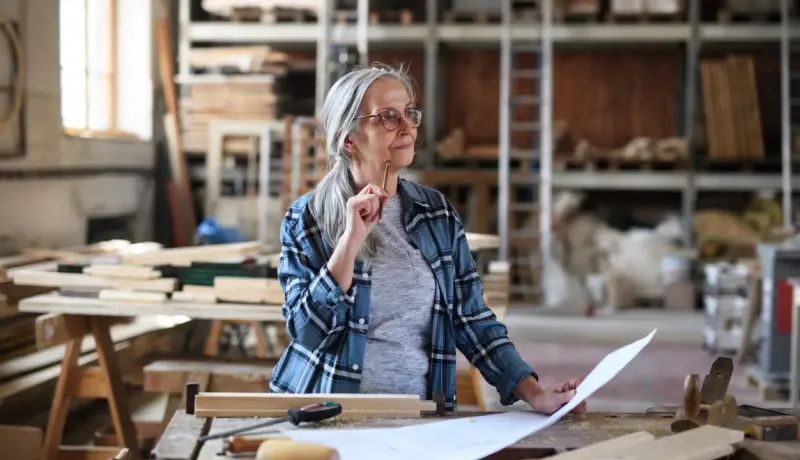 Une femme dans un atelier, tenant un document, concentrée sur son travail