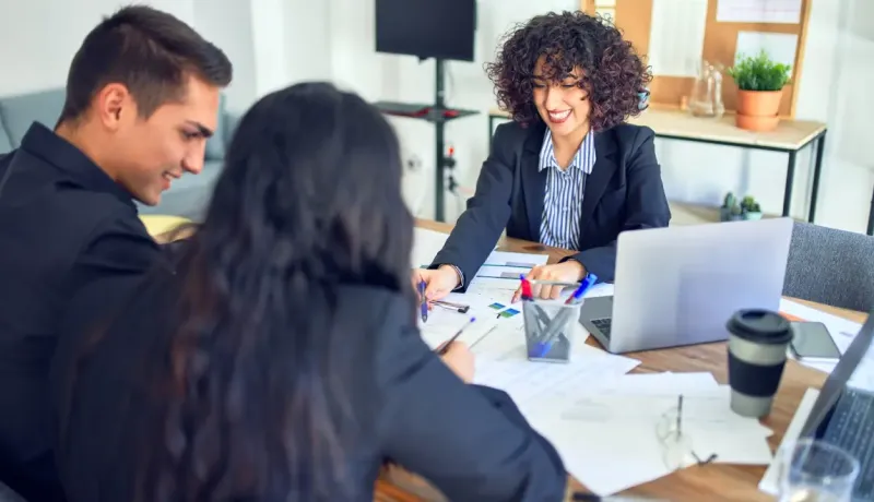 Trois personnes sont assises autour d'une table, regardant des documents.