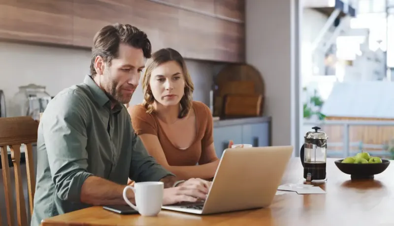 Couple en train de faire une recherche sur leur ordinateur portable.