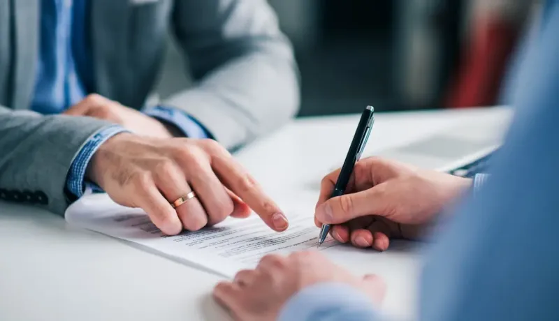 Une signature de contrat ou de document officiel est en cours, gros plan sur les mains.