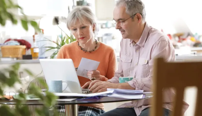 Un couple est en train de consulter des documents en utilisant un ordinateur portable.