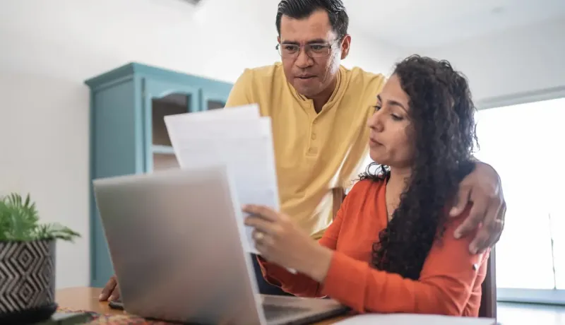 Un couple est en train de discuter sur des documents. Les personnes s'aident de leur ordinateur portable pour trouver des informations.
