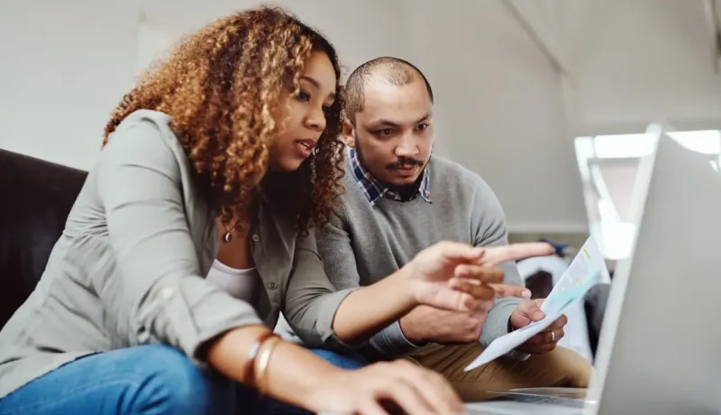 Un couple fait ses comptes en utilisant un ordinateur portable.