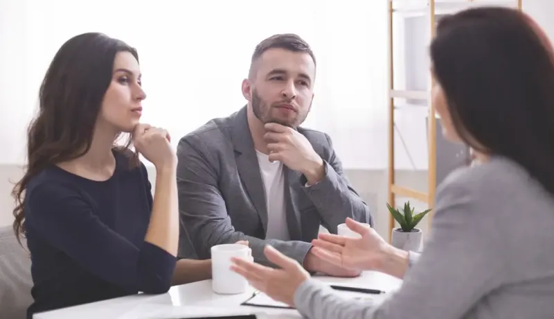 Un couple en train d'être conseiller par une femme.