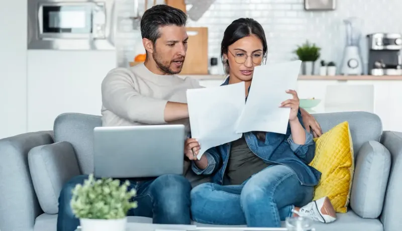 Homme et femme regardant des documents sur un canapé.