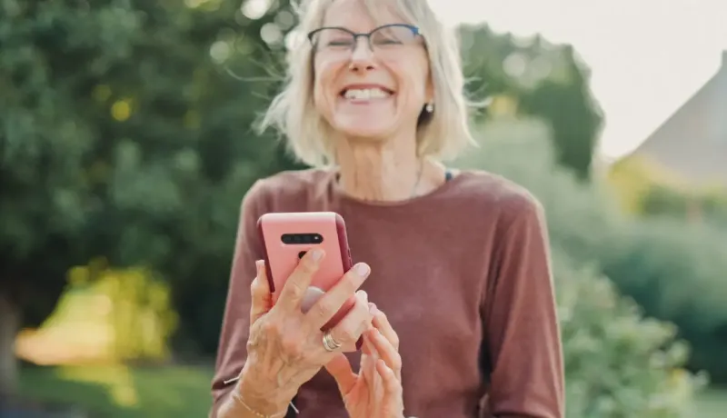 Femme senior utilise son smartphone en extérieur.
