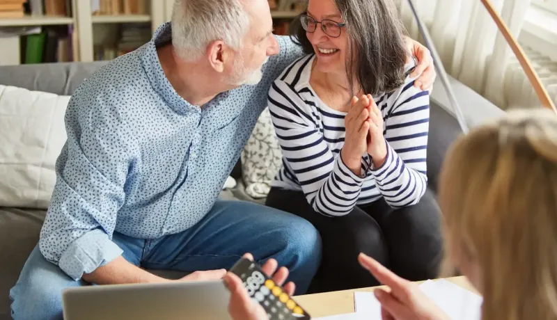 Couple utilisant un ordinateur portable sur un canapé, discutant des finances.