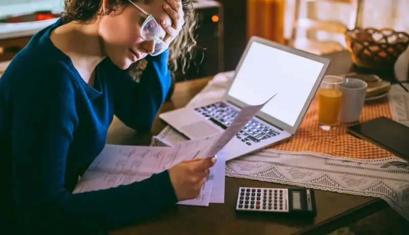 Jeune femme se tient la tête tout en consultant des documents