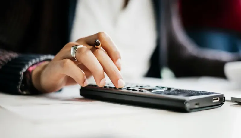 Gros plan montre des mains féminines utilisant calculatrice.