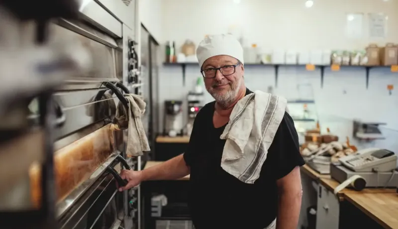 Un boulanger souriant attend que son pain cuit.