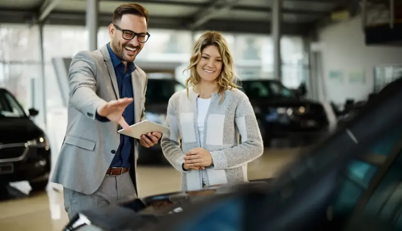 Un vendeur de voitures présente une voiture à un acheteur potentiel dans une salle d'exposition.